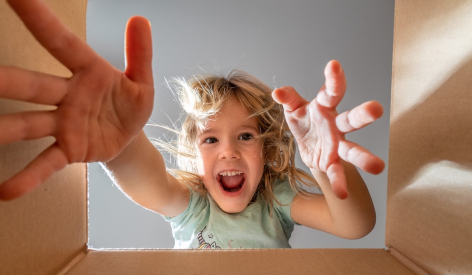 Happy,little,girl,is,opening,gift,and,looking,inside,cardboard